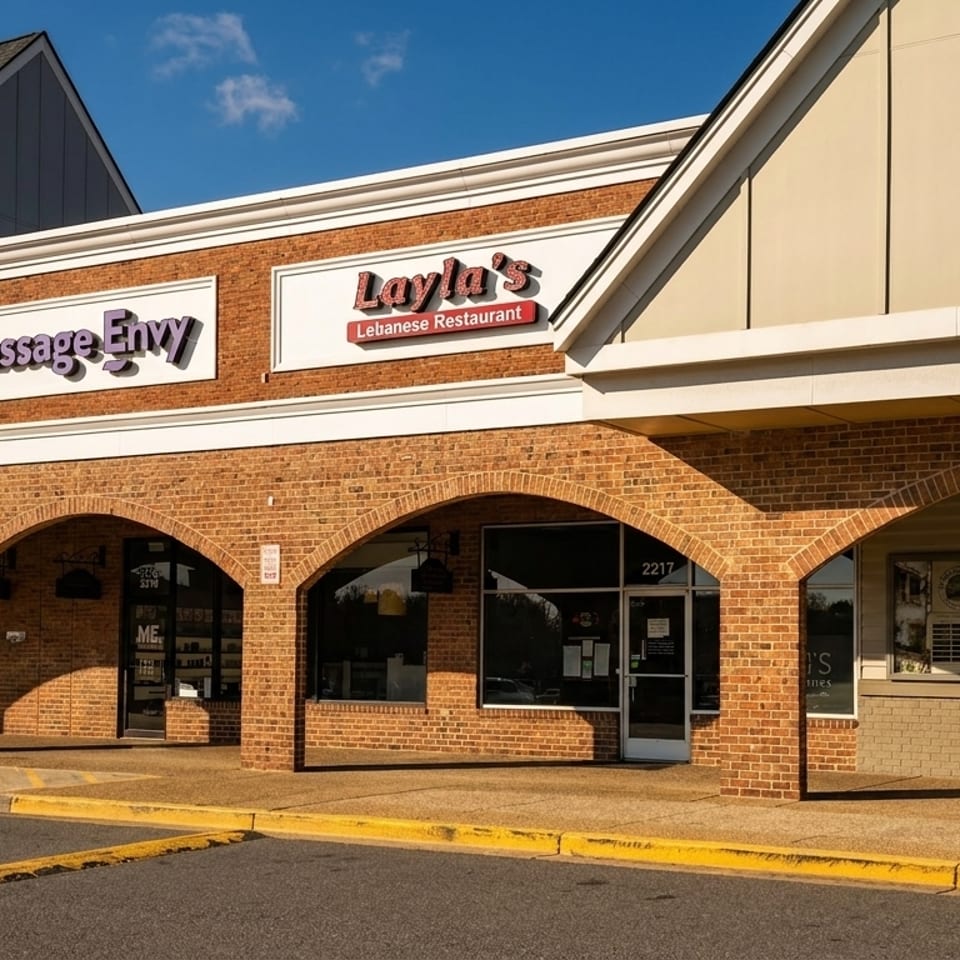 Layla's Lebanese Restaurant sign on a brick building with arched walkways and other businesses.