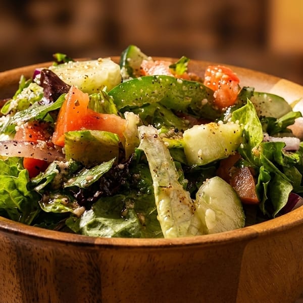 Fresh garden salad with lettuce, tomatoes, cucumbers, and onions in a wooden bowl.